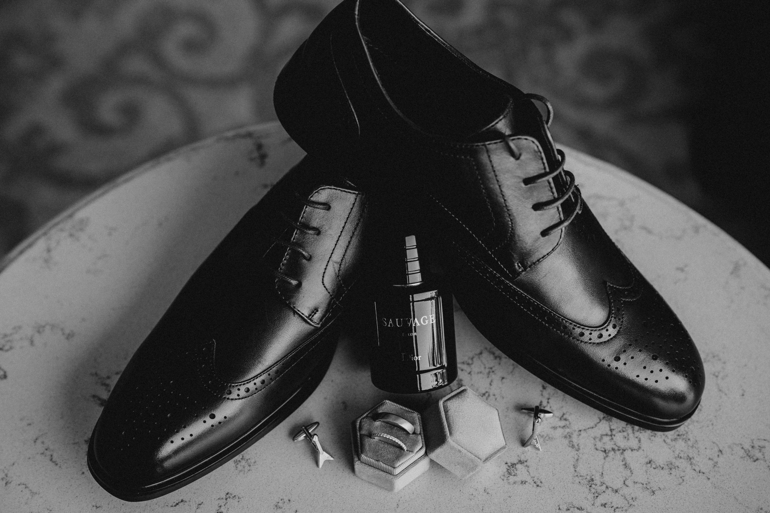 A collection of black leather dress shoes arranged in a row against a light background.