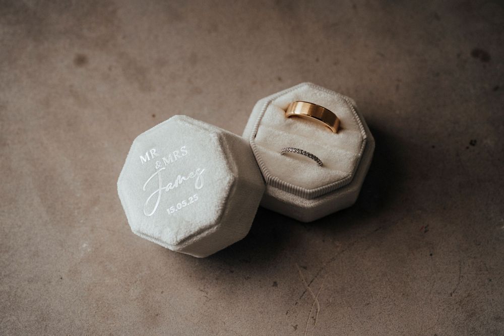 Small hexagonal marble ring boxes with calligraphy text arranged on a dark textured surface.