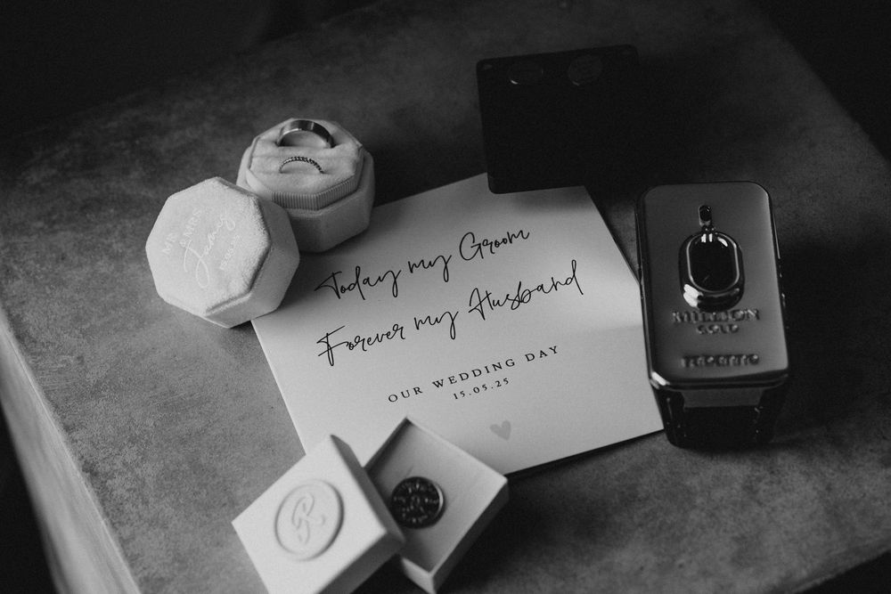Black and white photo of handwritten name cards and wine glasses on a dark surface at an elegant dinner setting.