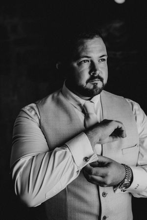 Black and white photo sequence showing someone in a light colored suit adjusting their tie in dramatic lighting.