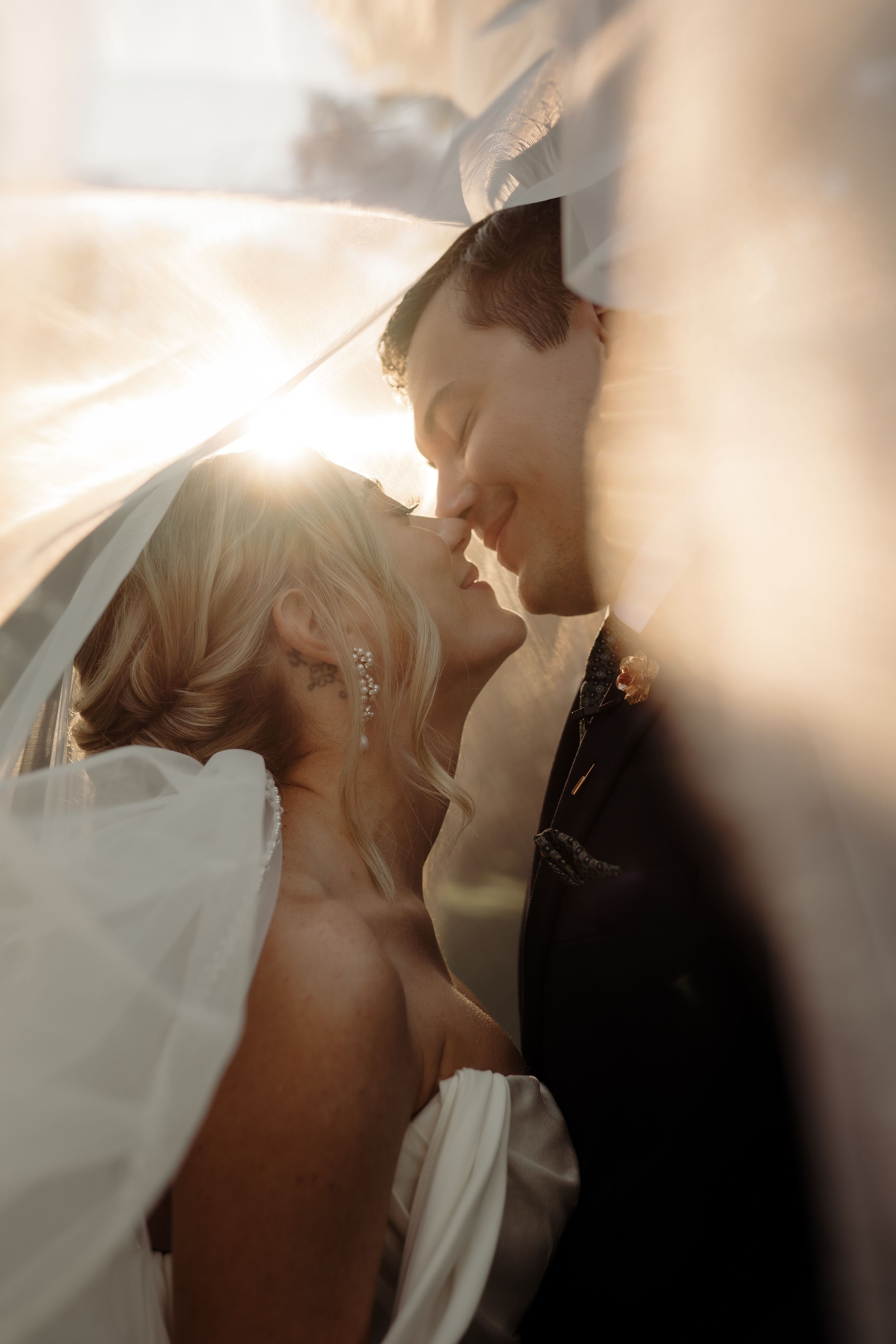 Intimate wedding photography with soft golden light filtering through a veil.