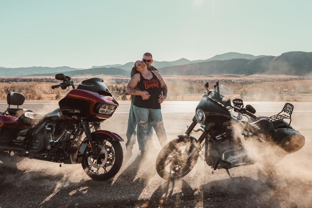 Three motorcycles parked on dusty road with riders gathering in desert landscape.