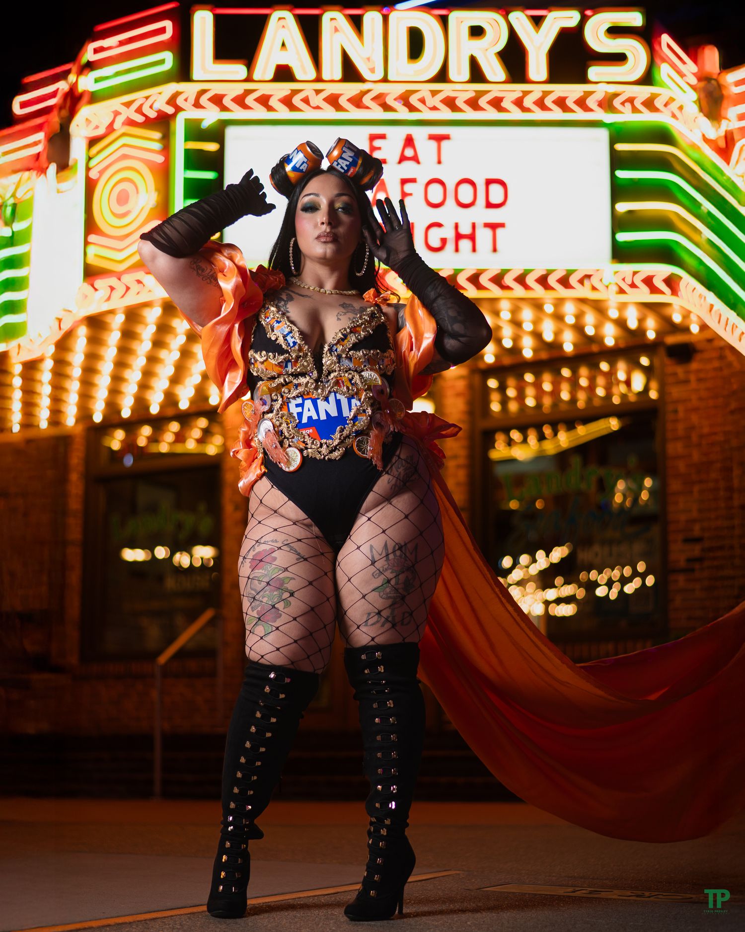 Illuminated retro Landry's casino sign at night with someone posing in fishnet stockings and boots on the strip.