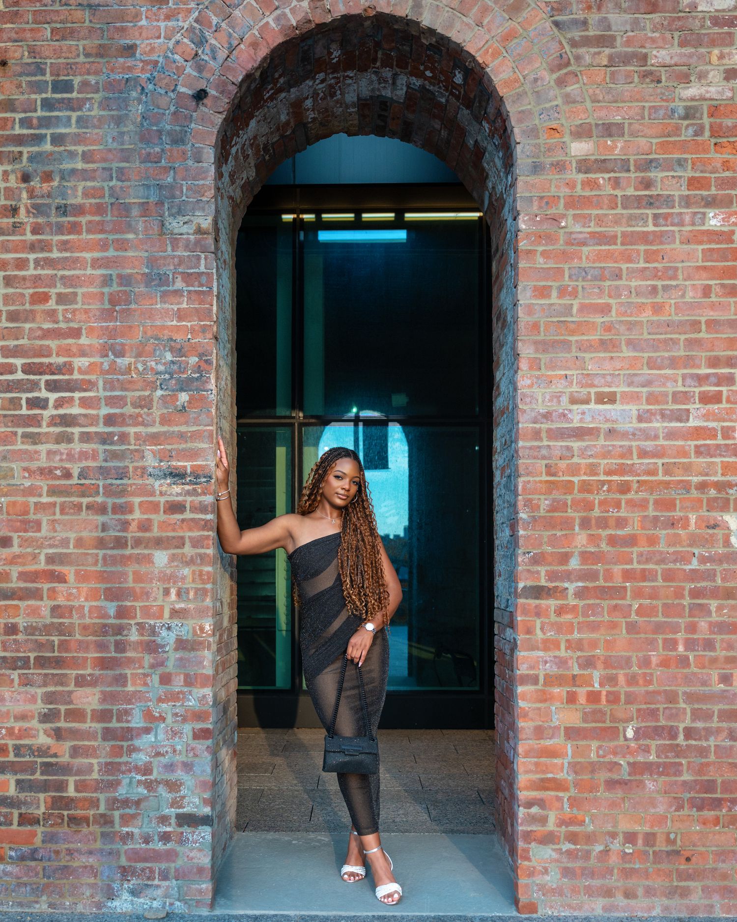 Series of figures in a brick archway demonstrating dance-like movements against a red brick wall.