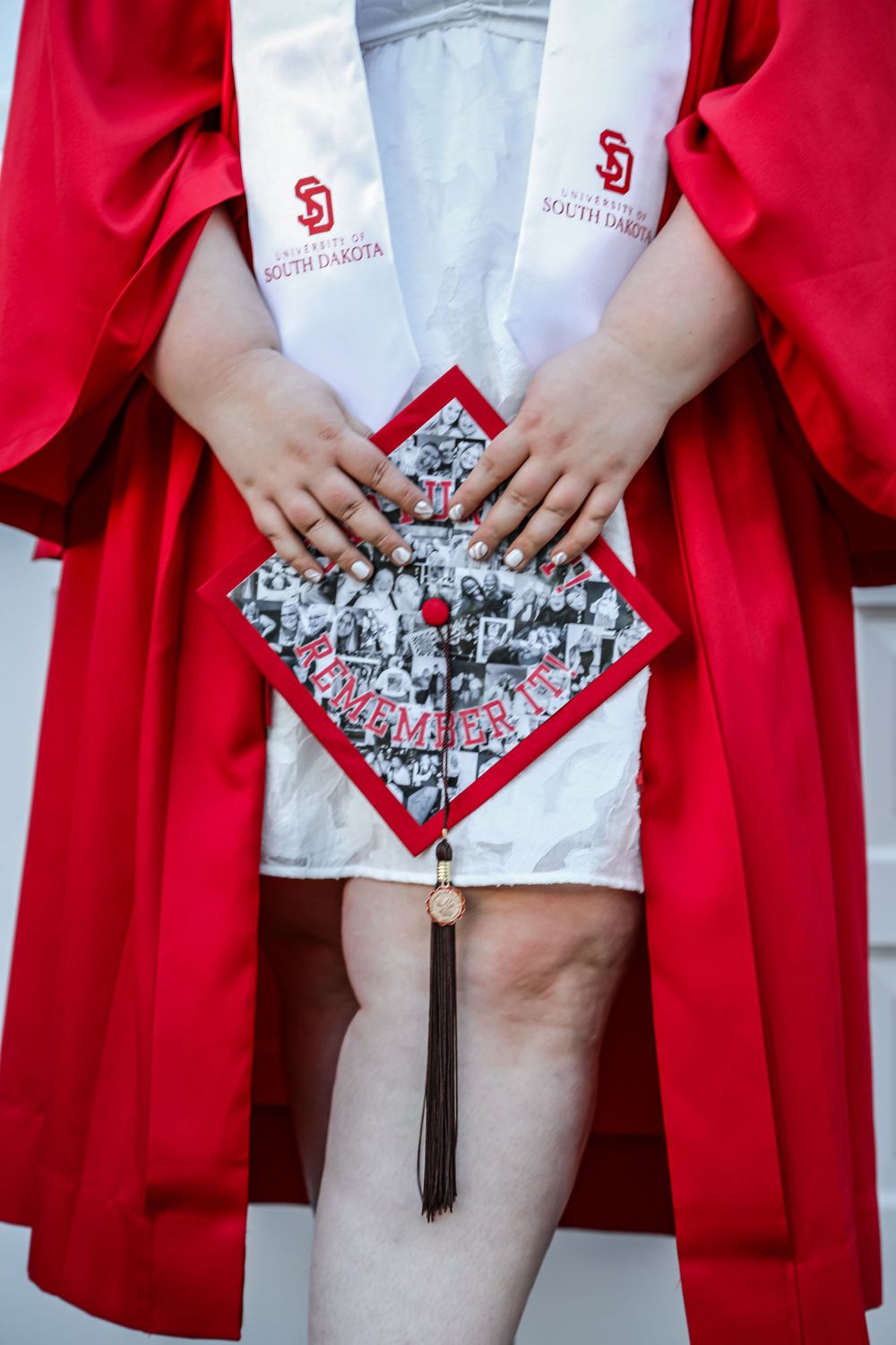 Close-up of decorated graduation cap with photo collage and red trim.