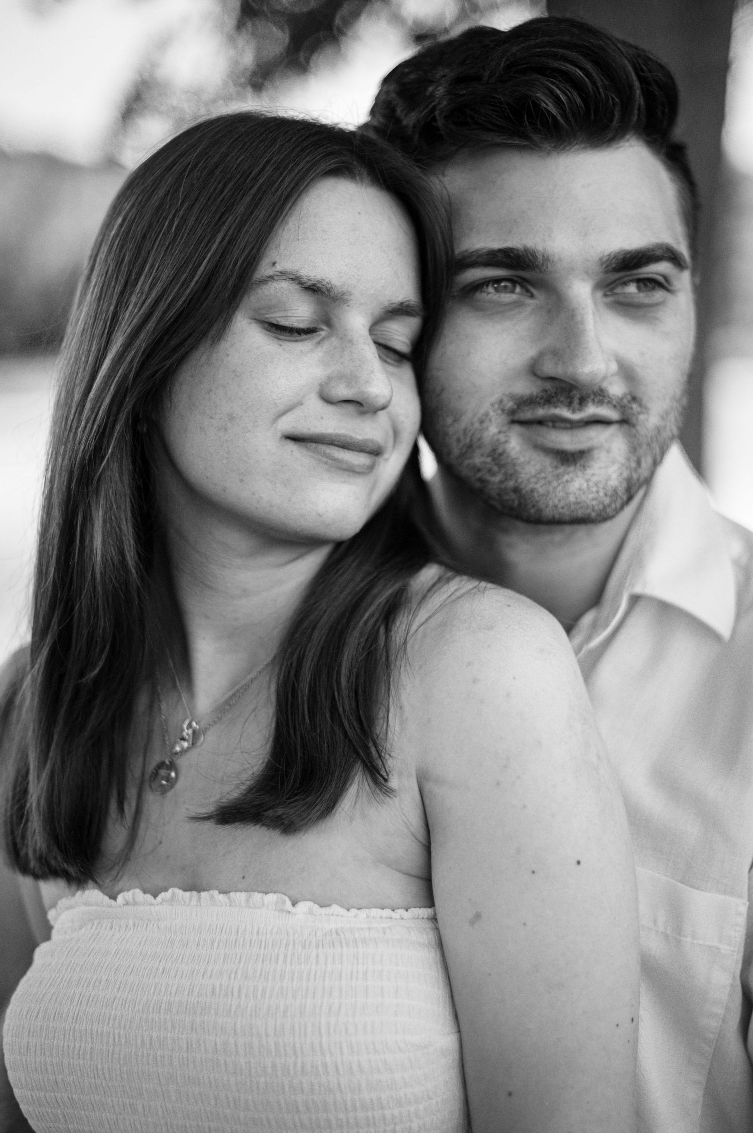 Ein romantisches Schwarz-Weiß-Porträt eines Paares, das sich umarmt, wobei die Frau ihren Kopf an ihren Partner lehnt.