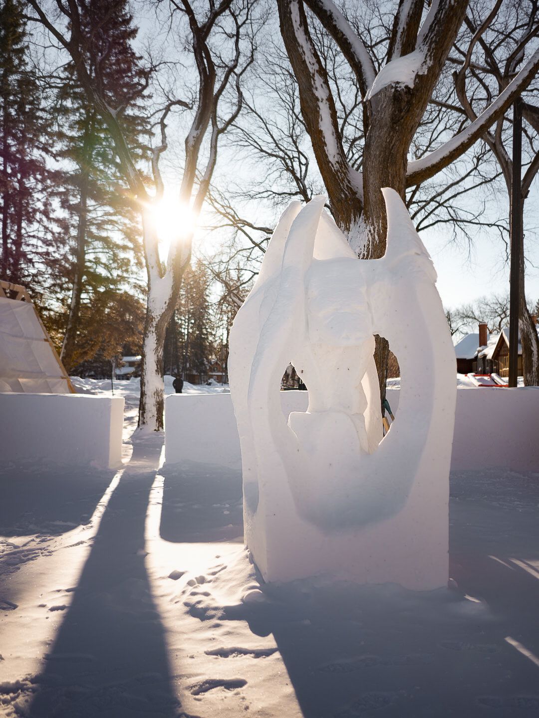 Large ice sculptures glow in the winter sunlight against a snowy landscape.
