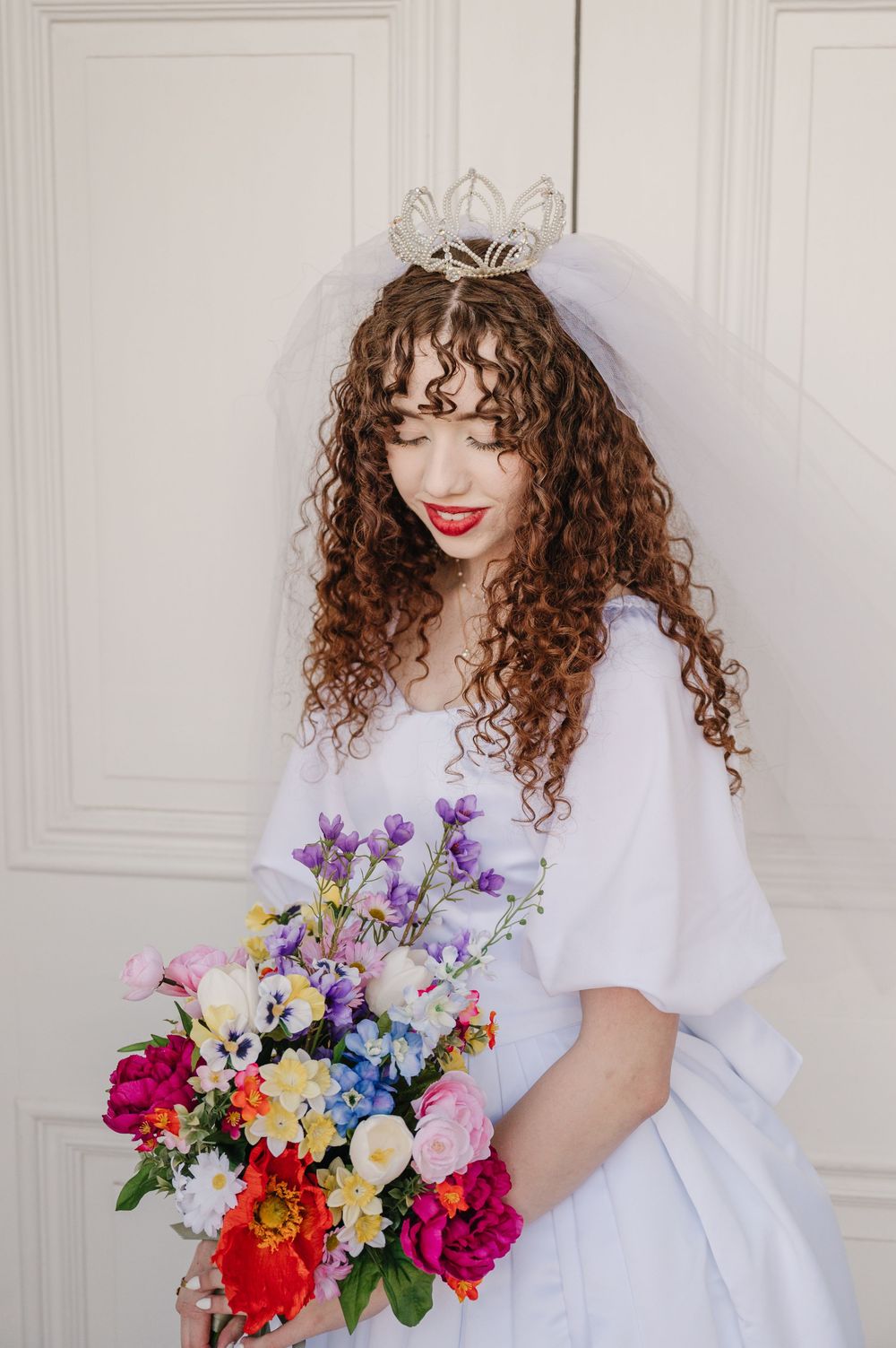 A bridal portrait showcasing a vibrant colorful bouquet, flowing veil and delicate tiara.