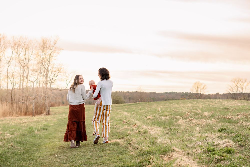 Two people sitting together on a grassy hilltop at sunset.