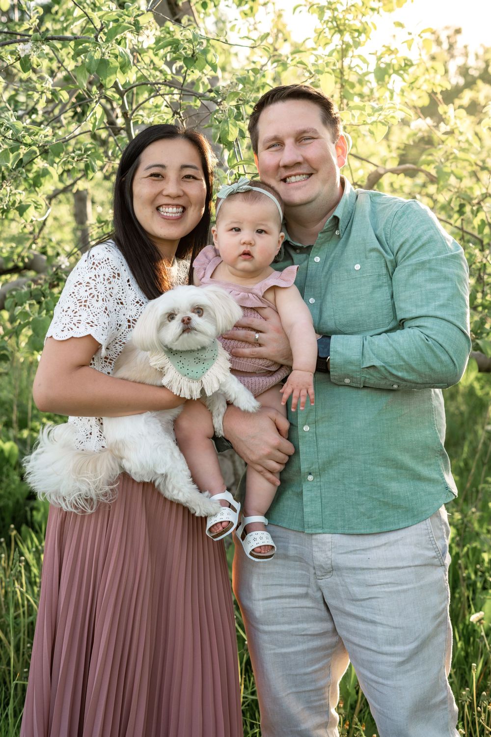 Family portrait with small dog in a blooming spring garden setting.