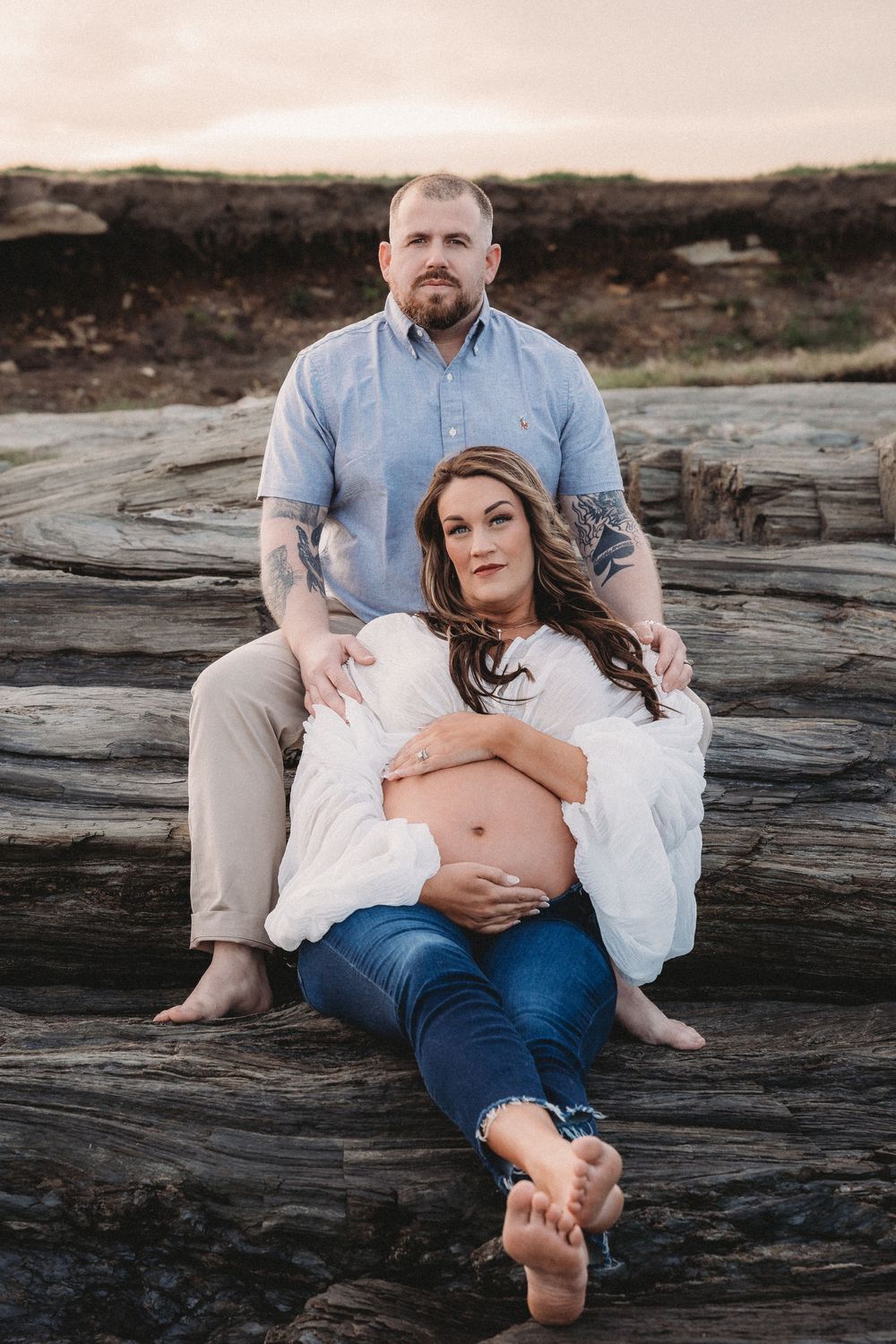 Maternity photography session featuring casual poses on rocky coastal landscape.