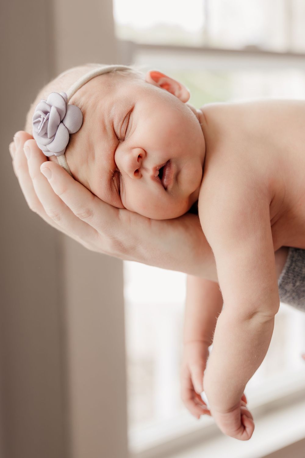 Peaceful newborn baby sleeping during studio photography session with natural lighting.