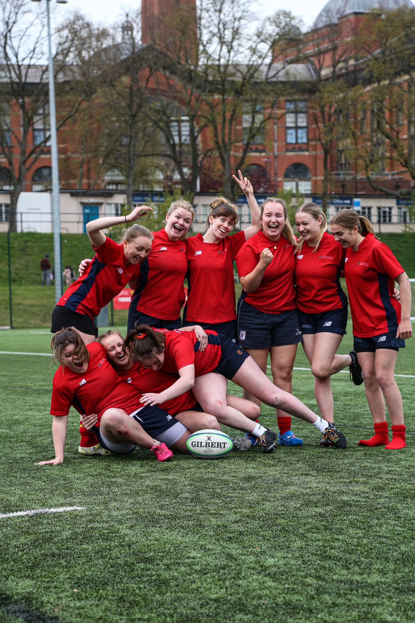 Group photo after a rugby sevens tournament at the University of Birmingham, with players falling over and everyone laughing.