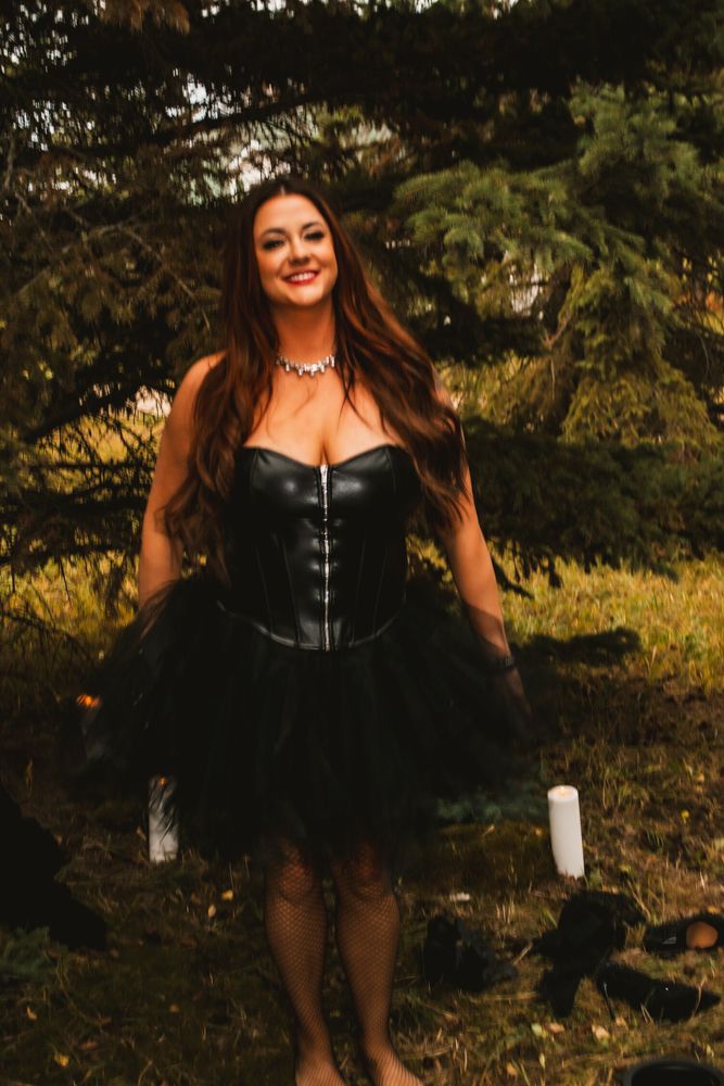 Gothic styled portrait in black tulle dress against forest background.