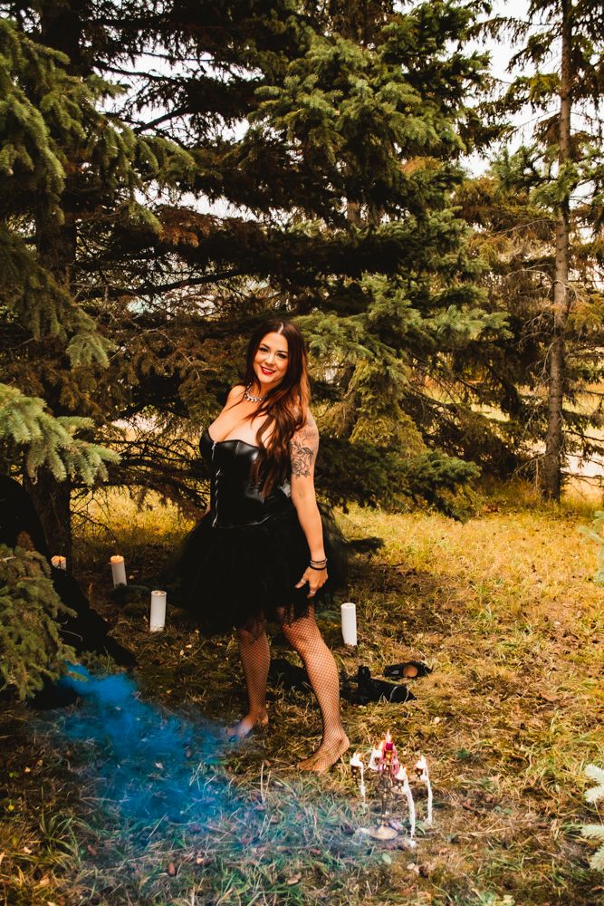 Forest photoshoot featuring black dress and blue smoke with decorative ground elements.
