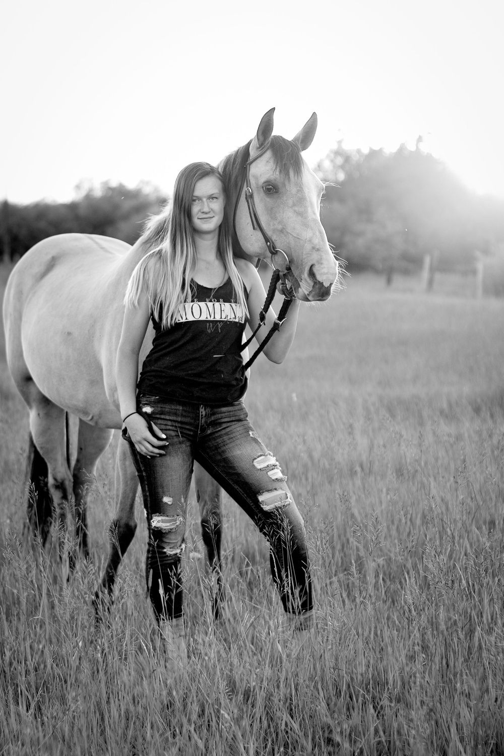 Black and white photos of a person with a white horse in a grassy field.