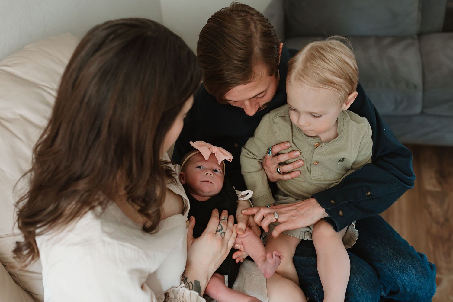 A candid moment captured on a couch as family members gather around together looking at something. Colorado Springs Photographer.