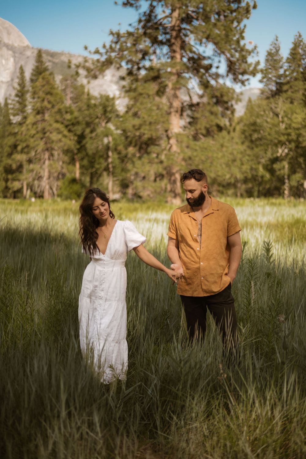Couple shares tender moments in a mountain meadow with dramatic peaks in the distance.
