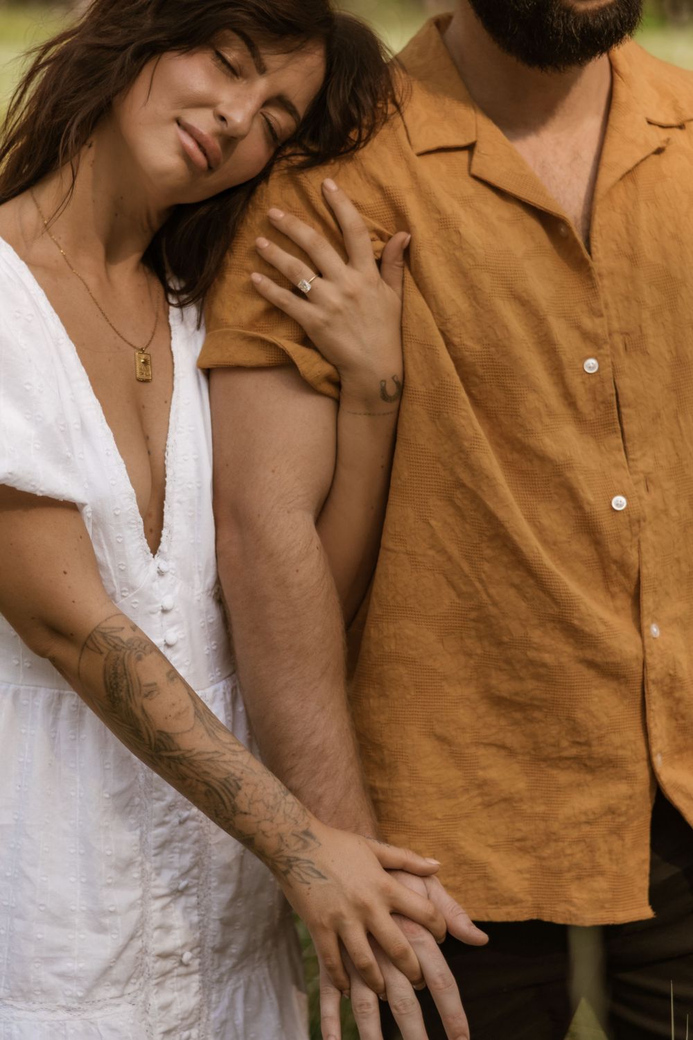 Close-up shot of two people in white and mustard clothing embracing outdoors.