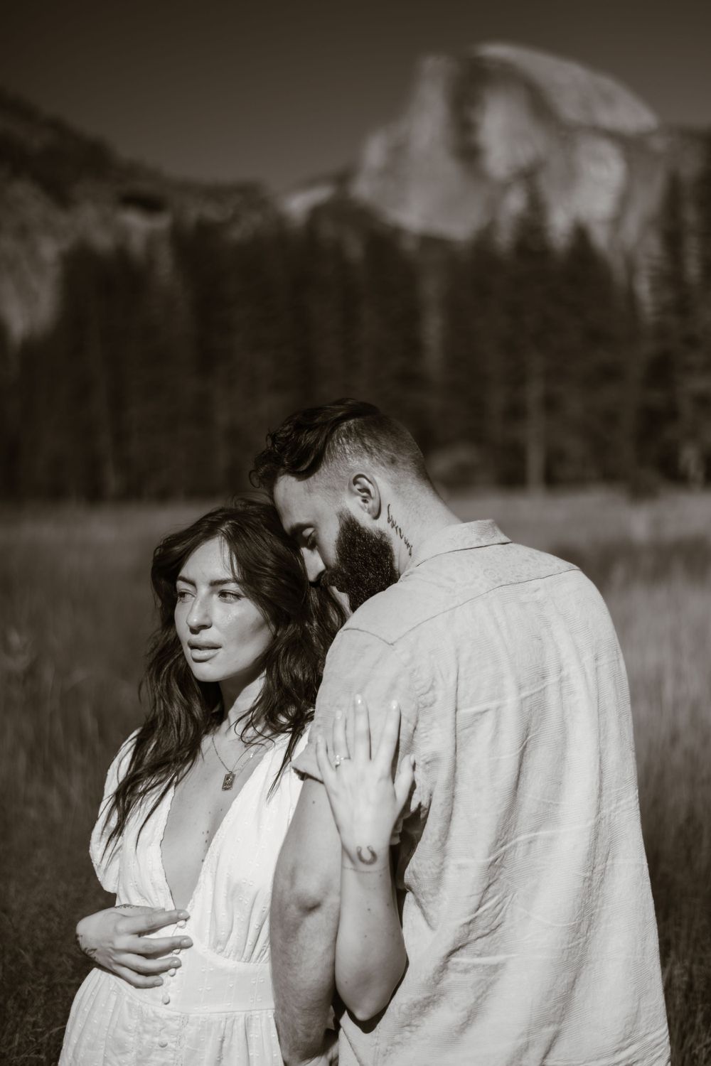 Intimate black and white portrait of a couple with mountain scenery in the background.