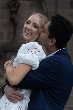 A romantic embrace between a couple in formal wedding attire, with the bride wearing a white lace dress.