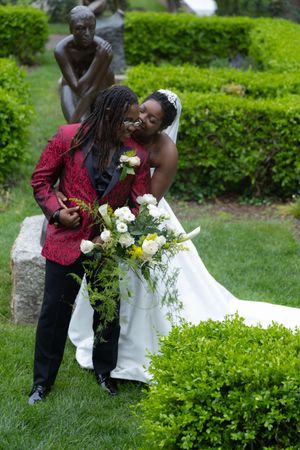 Wedding photo session showing couple in burgundy and white attire posing in lush garden setting.