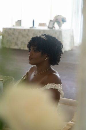 An elegant bridal portrait captured through soft focus with natural curls and off-shoulder dress.