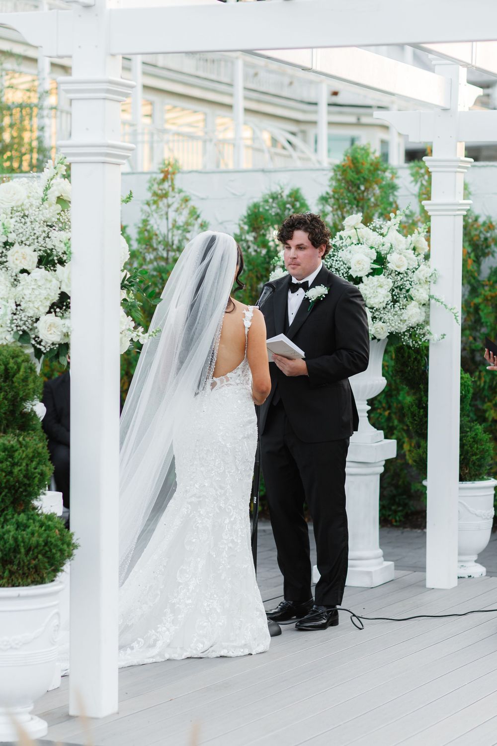 Wedding ceremony sequence with white columns and floral decorations on an outdoor terrace.