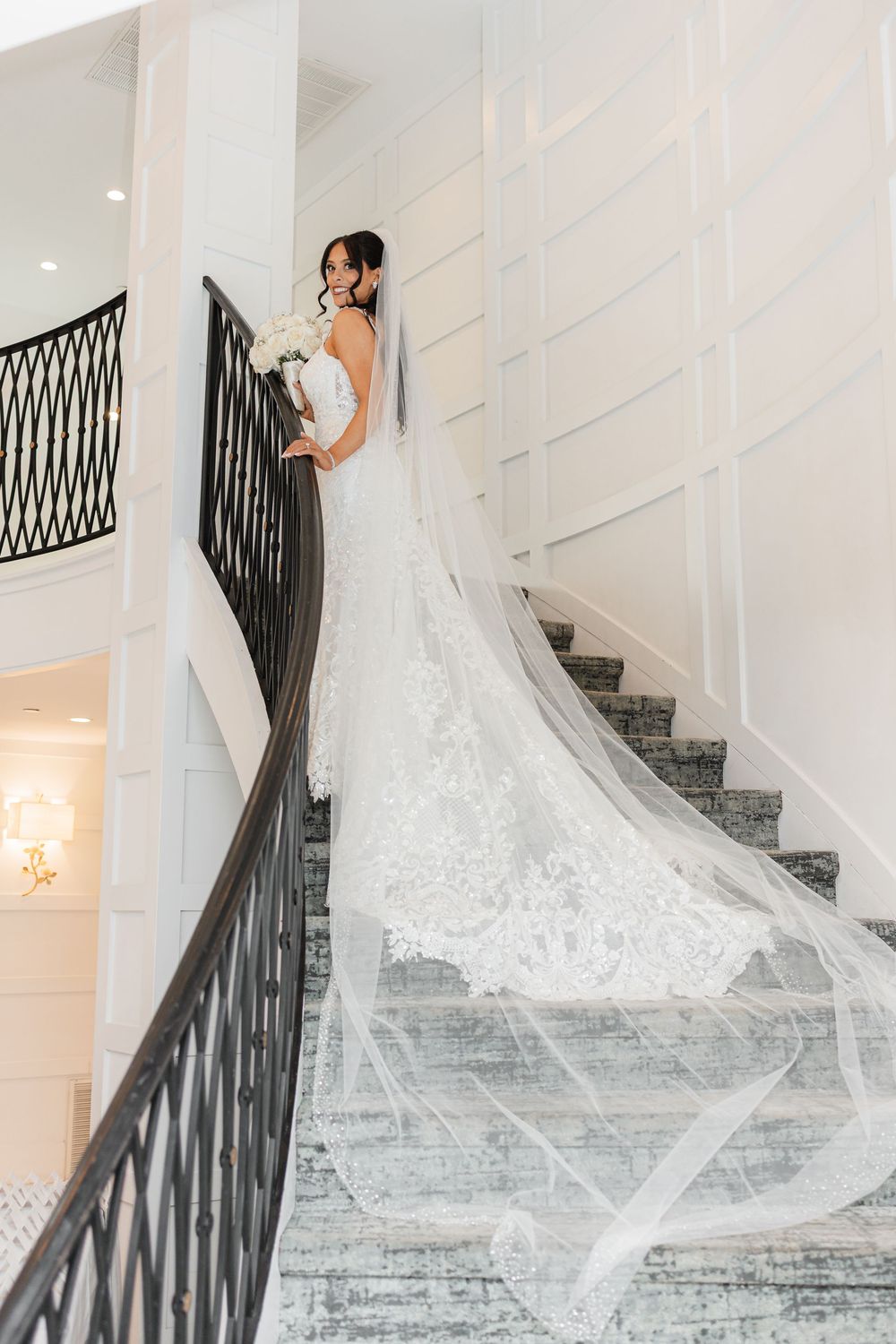 Elegant bridal portrait sequence on grand white staircase with flowing veil and train.