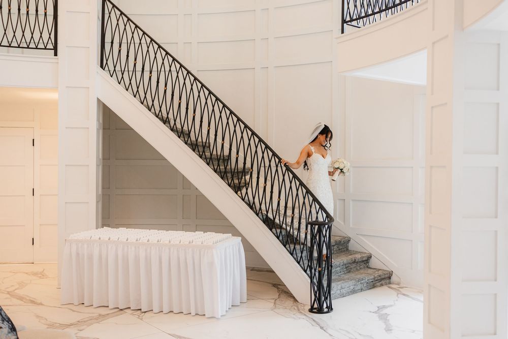 Elegant white staircase with black wrought iron railings curves upward in a modern minimalist interior space.