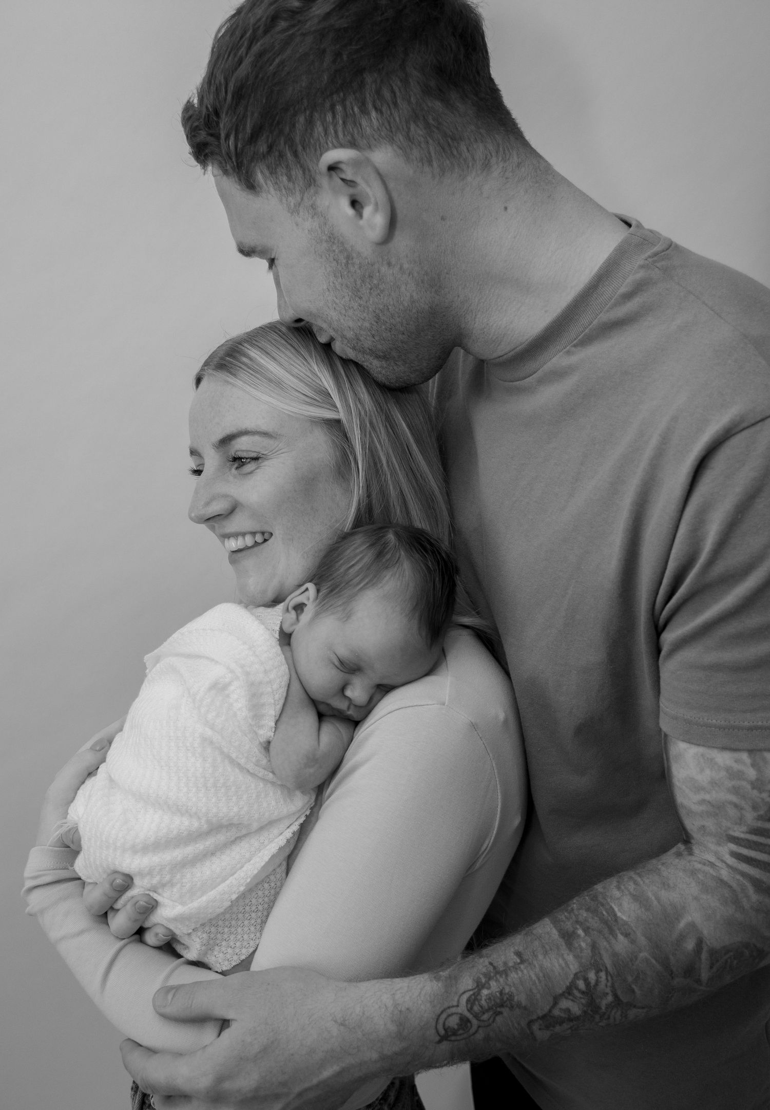 Black and white intimate family portrait showing tender moments between parents and baby. Newborn Photoshoot