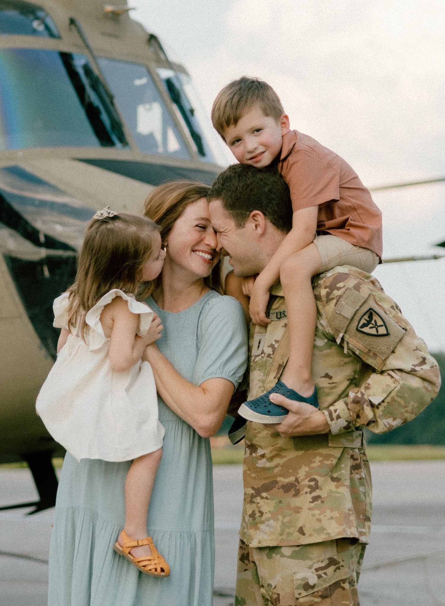 A military family photo session. Military homecoming moment in front of a large Chinook helicopter on an airfield at an Air Force base.