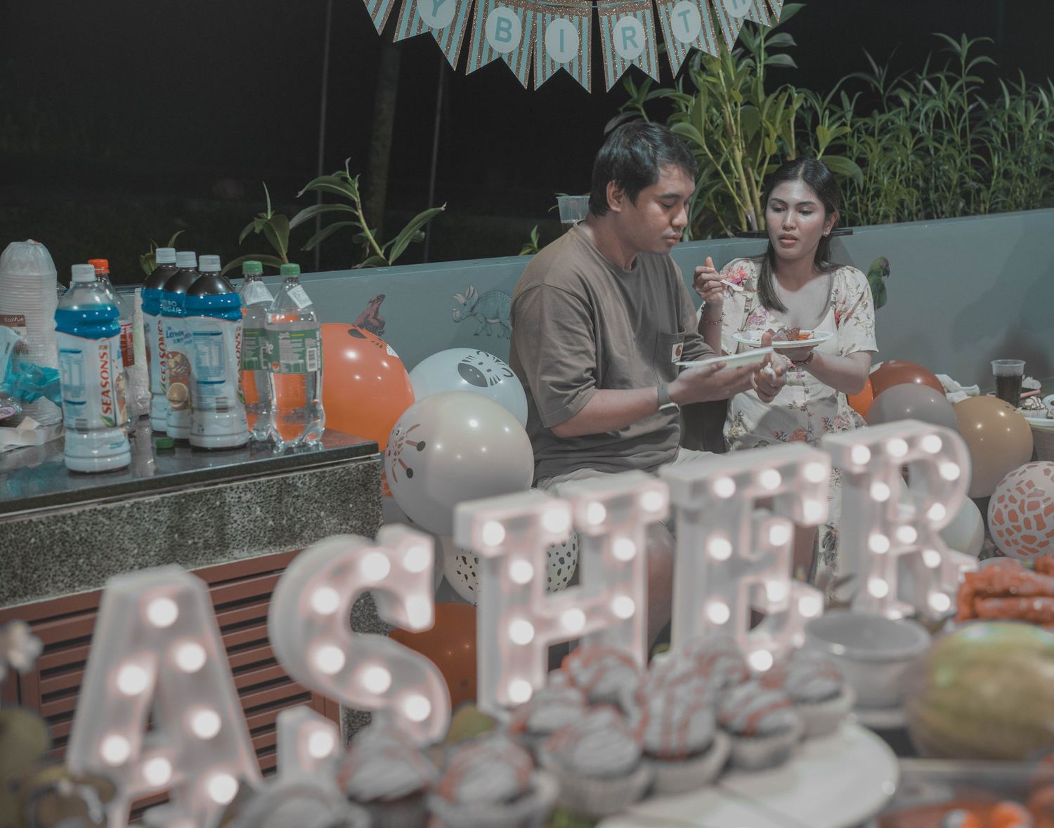 A party setup with illuminated ASHER letters and refreshment table.