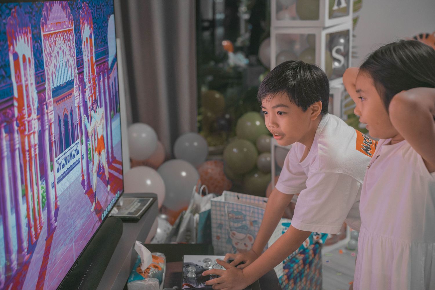 Children watching an illuminated screen display at a birthday party.