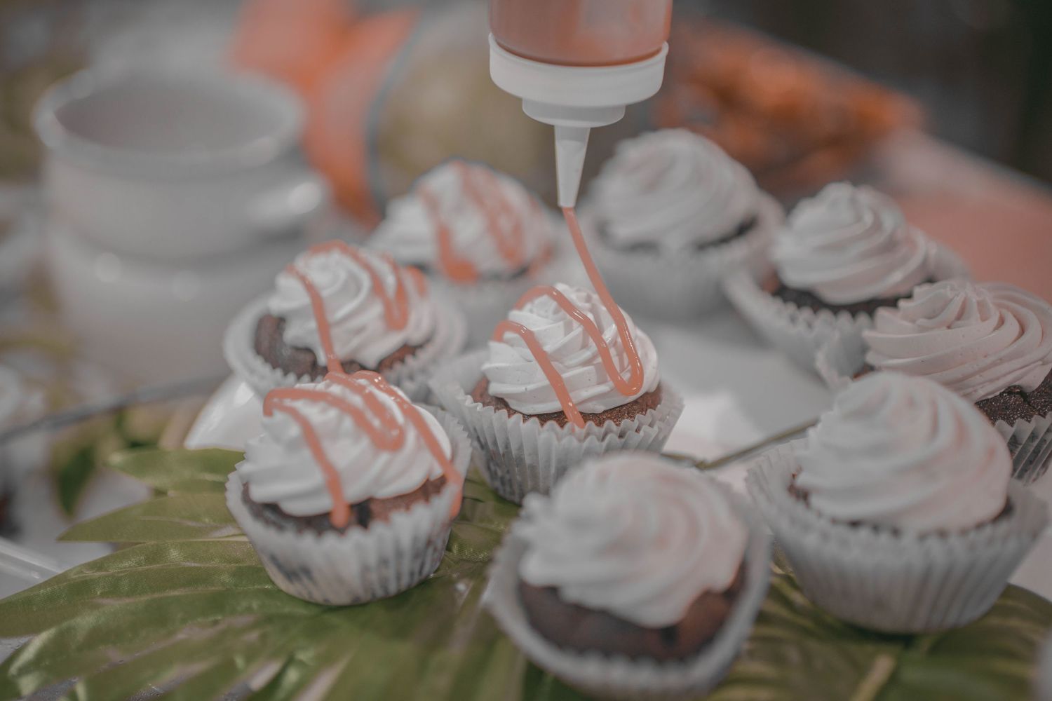 Close-up of frosted cupcakes with coral-colored decorative toppings.