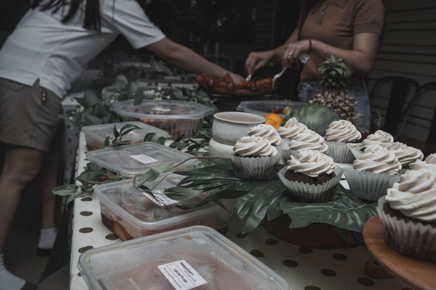 Cupcakes and party food arranged on a table with greenery decorations.