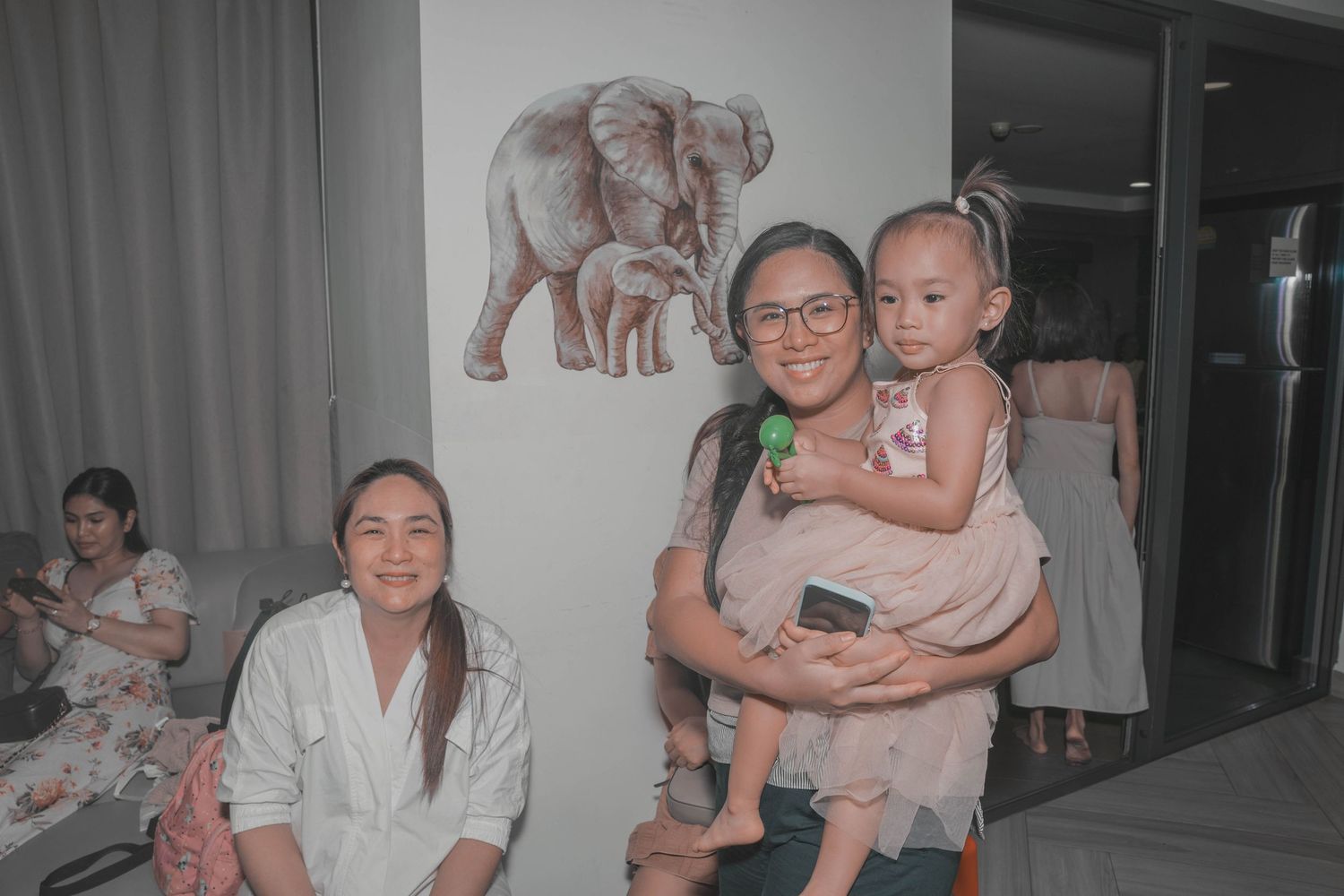 Intimate gathering in a living room with elephant artwork on the wall.
