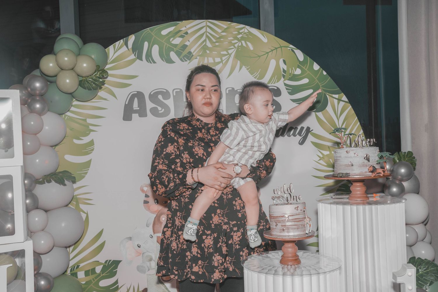 Tropical-themed first birthday party with balloon arch and decorative backdrop.