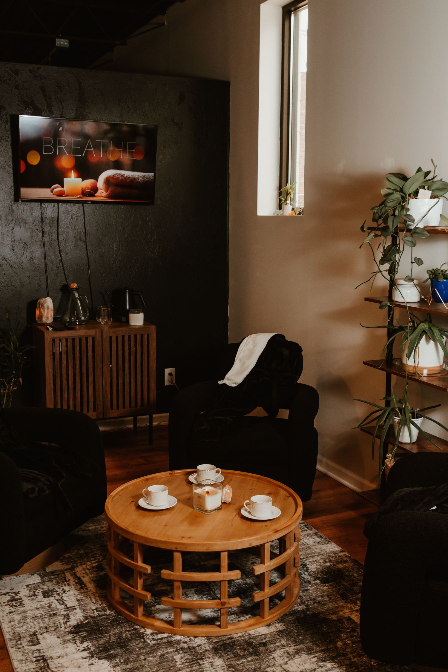 A cozy coffee table setting in a dark room with white cups and natural light streaming through the window.