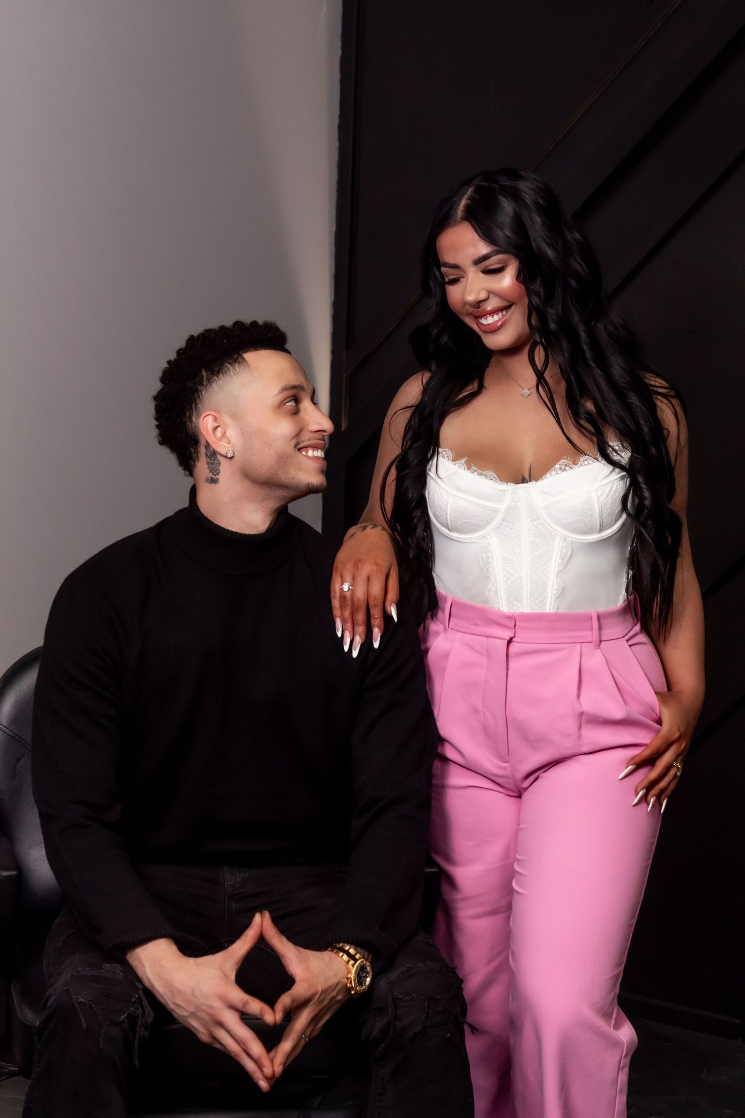 Stylish couple posing together in contrasting black and white outfits with pink accents.