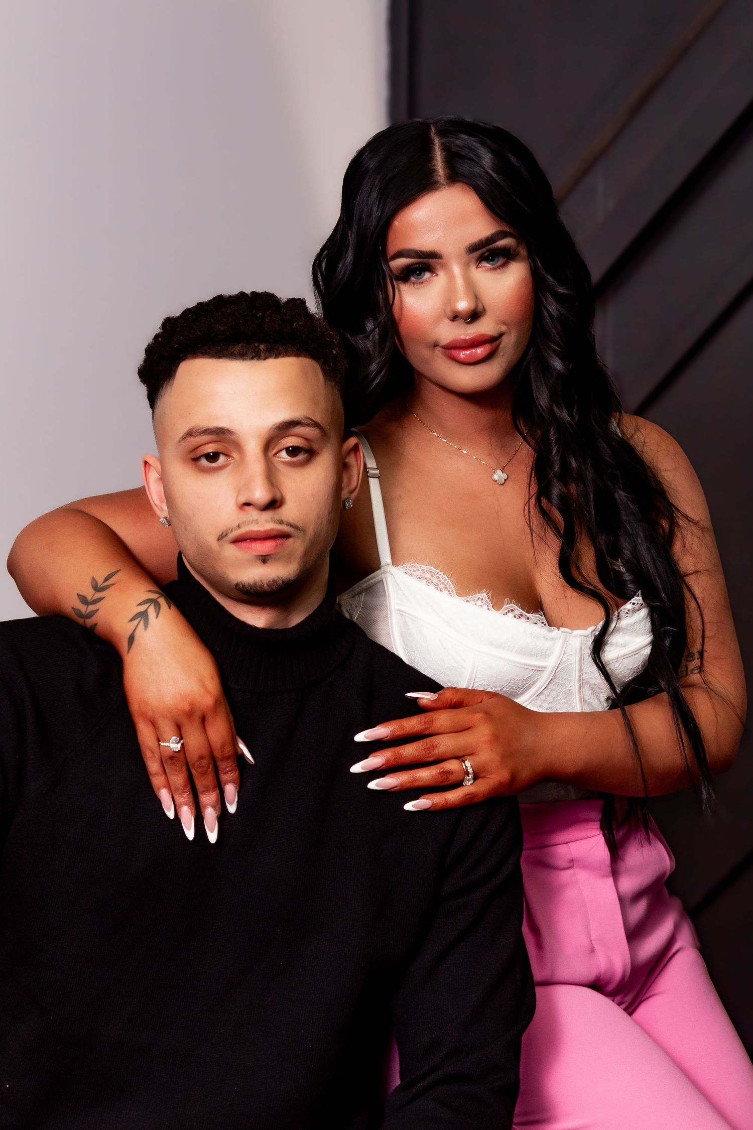 Fashionable couple in coordinated outfits posing for a professional studio portrait.