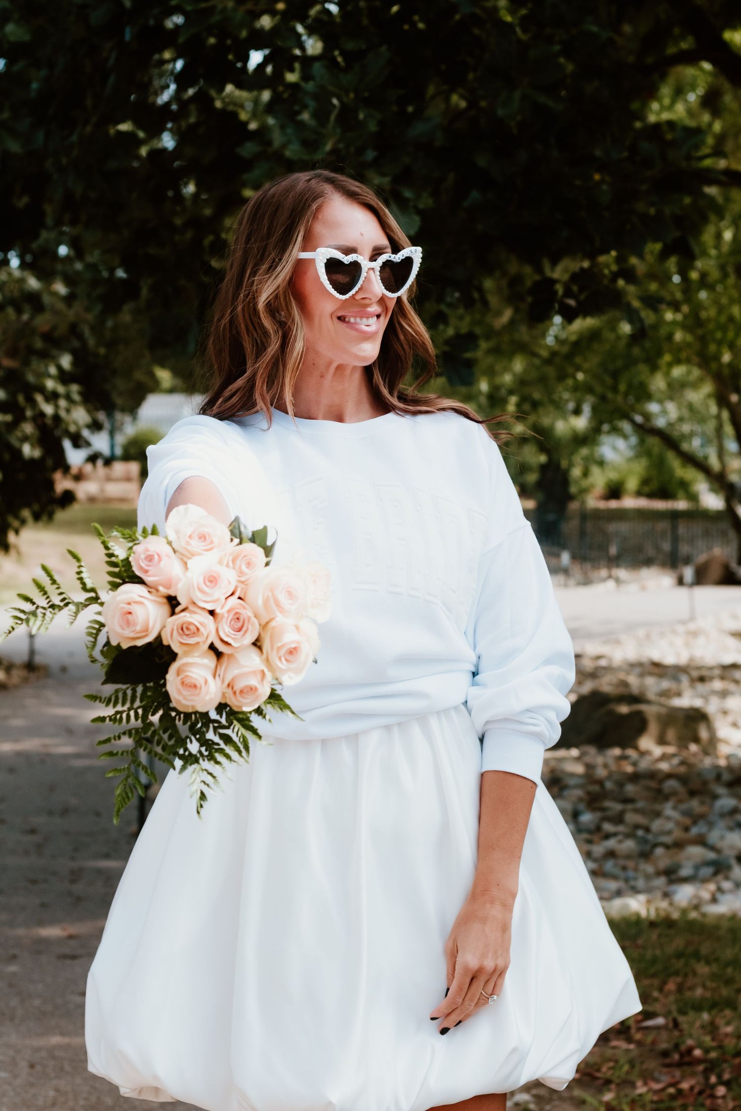Casual bridal look with heart sunglasses and pink roses in white sweater dress.