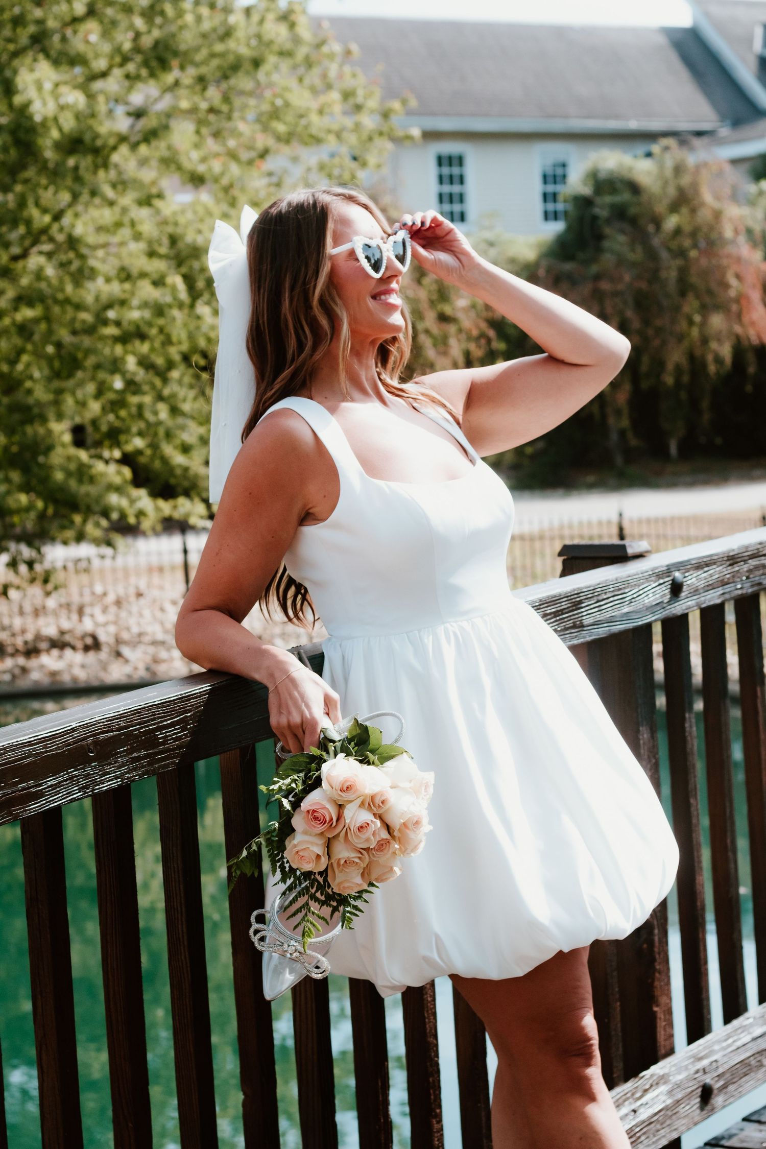 White summer dress and heart sunglasses with bouquet on outdoor wooden deck.