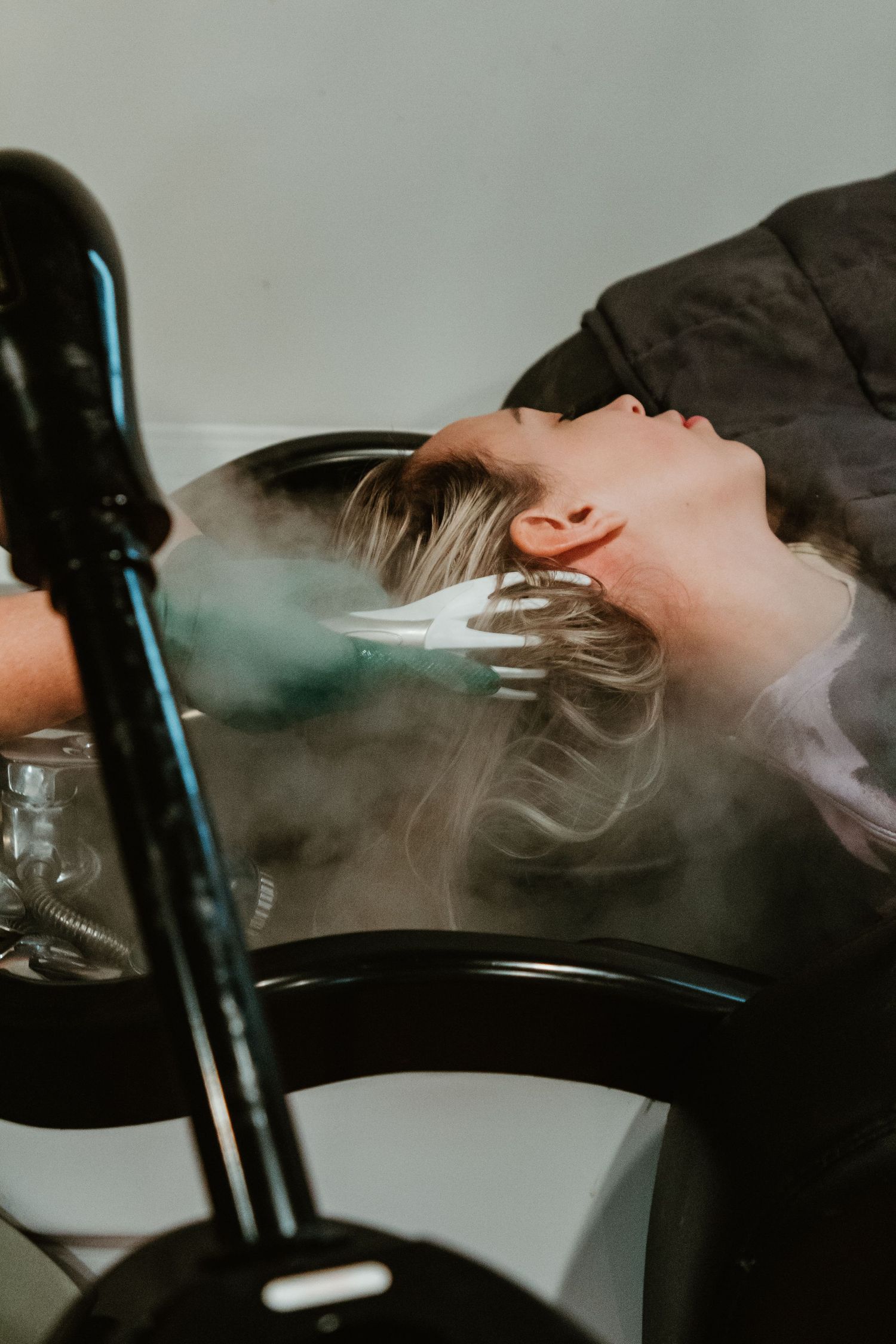 Steam rises as client receives luxurious hair wash treatment at salon basin.