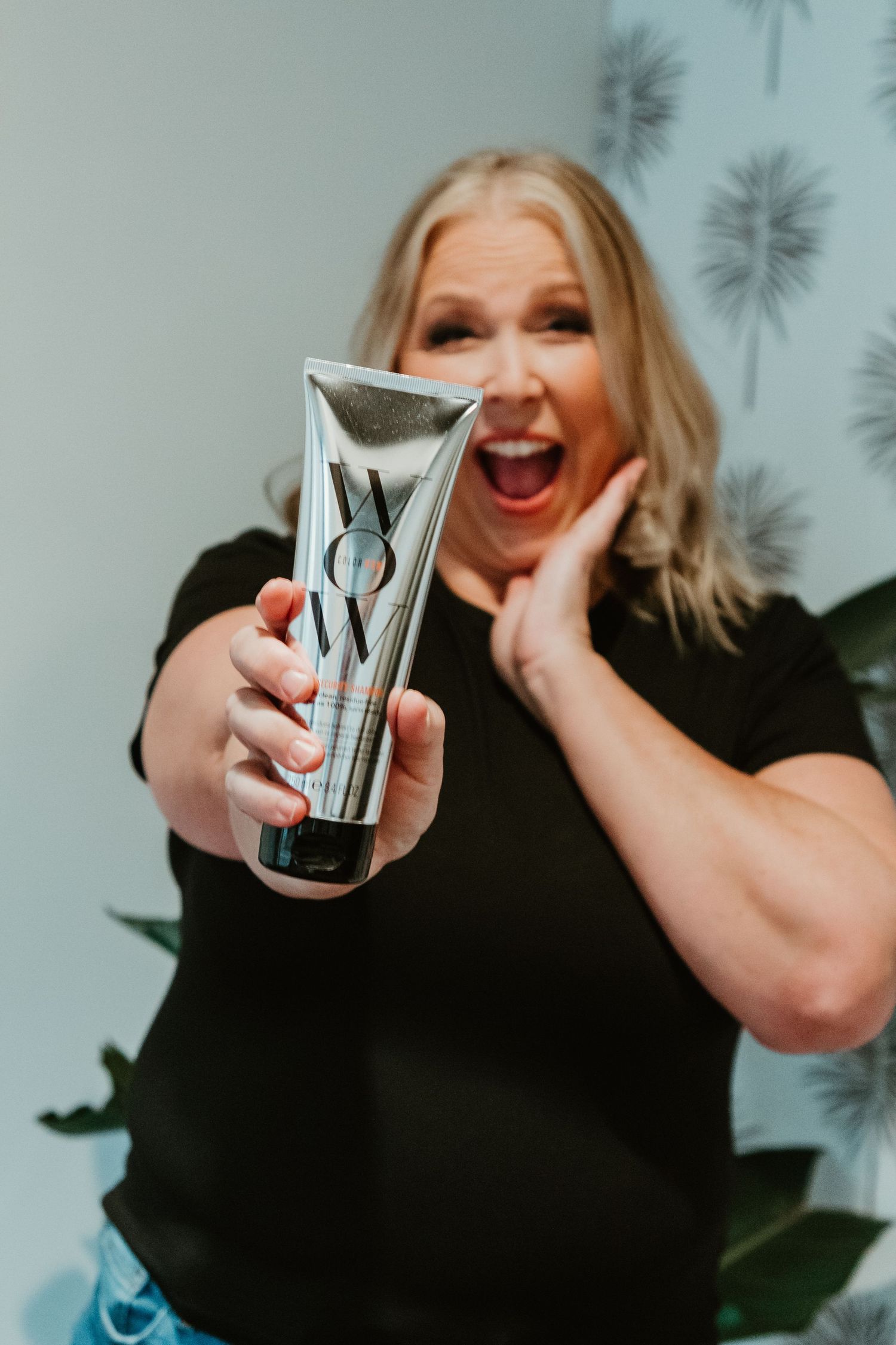 Enthusiastic expression while holding up a beauty product award or trophy.