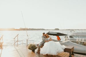 Couple shares intimate moment on scenic wooden dock overlooking calm waterfront at sunset.