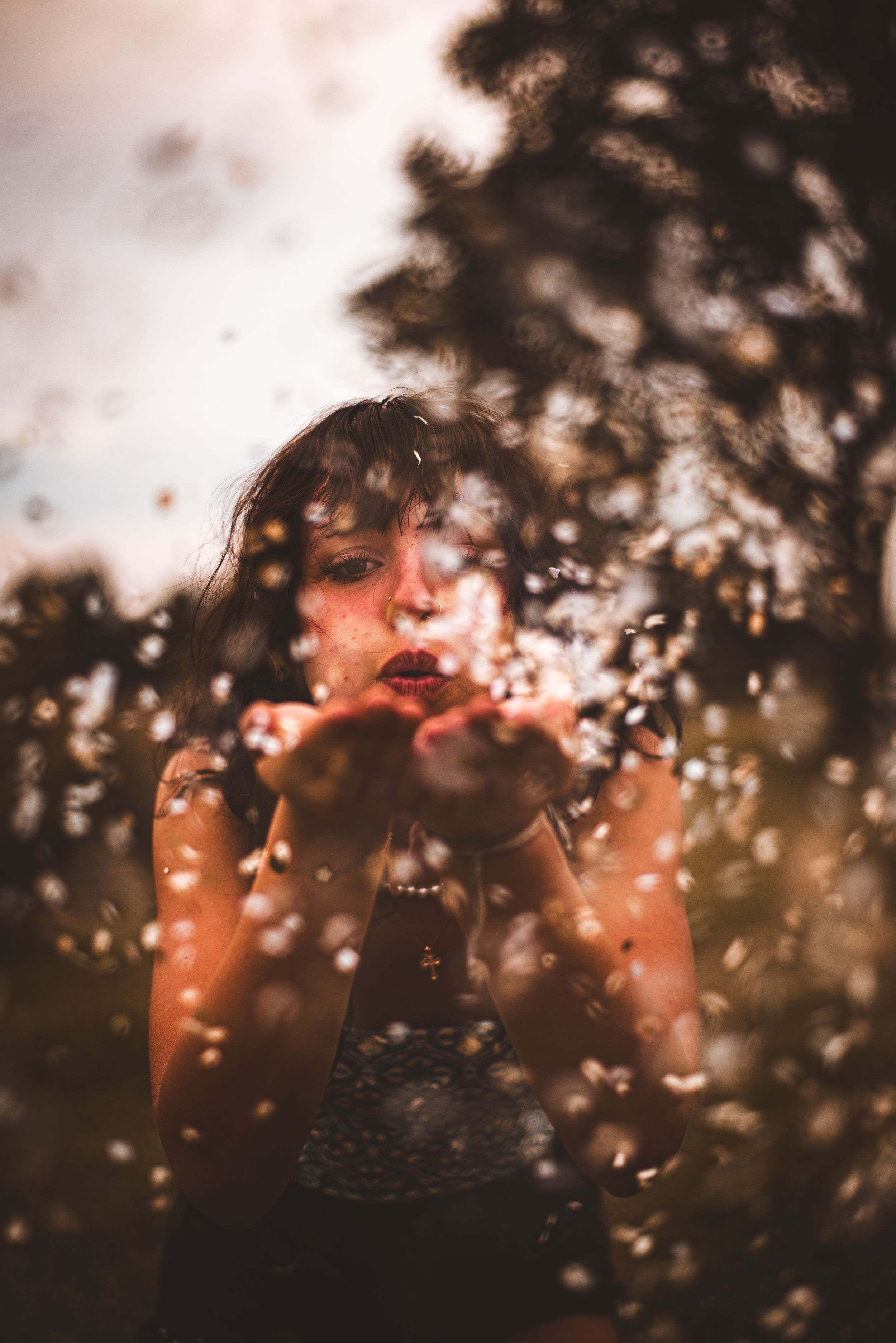 Artistic portrait taken through blurred confetti capturing a dreamy summer moment at golden hour.