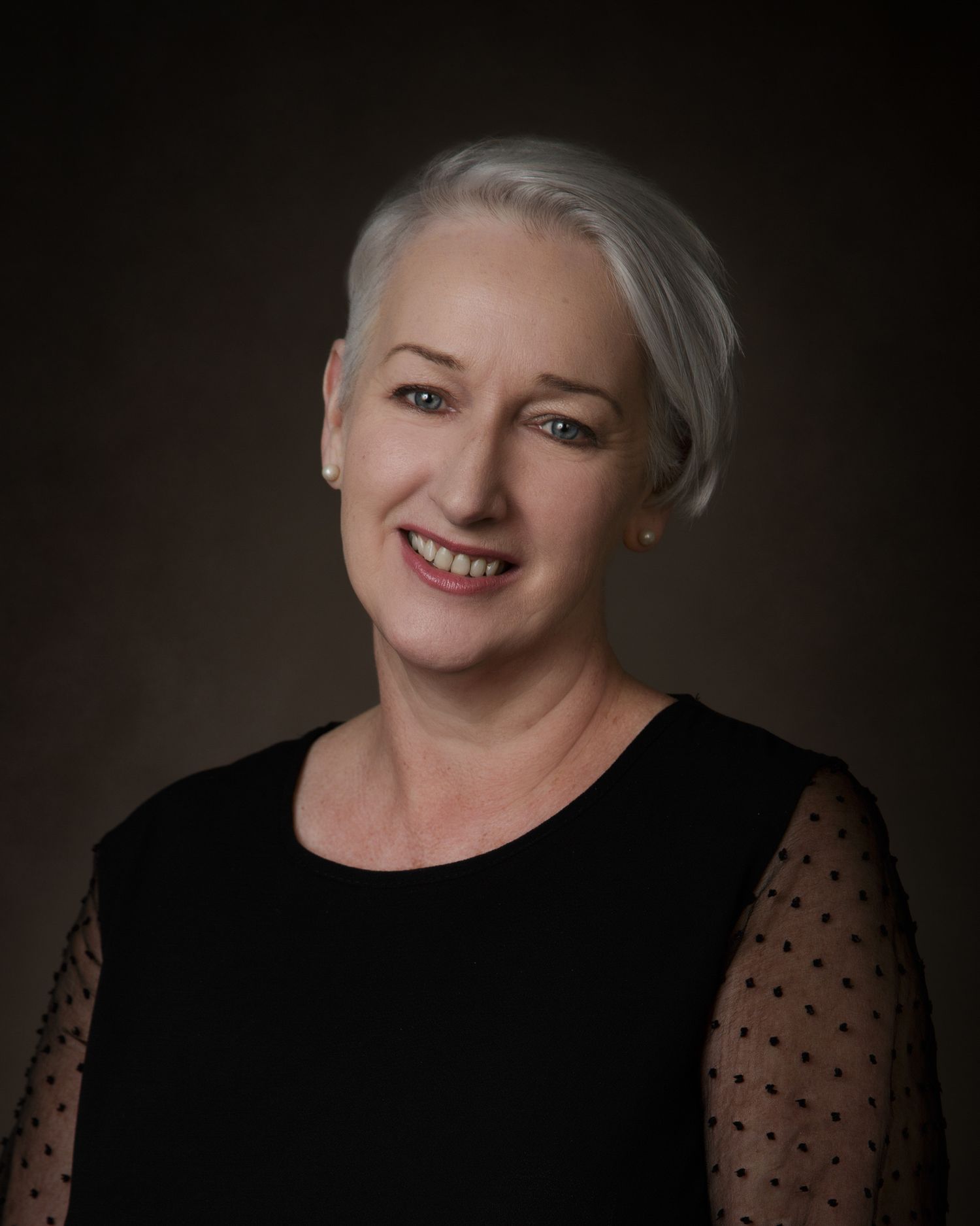 A woman with white hair wearing a black top, exuding elegance and confidence in her appearance.