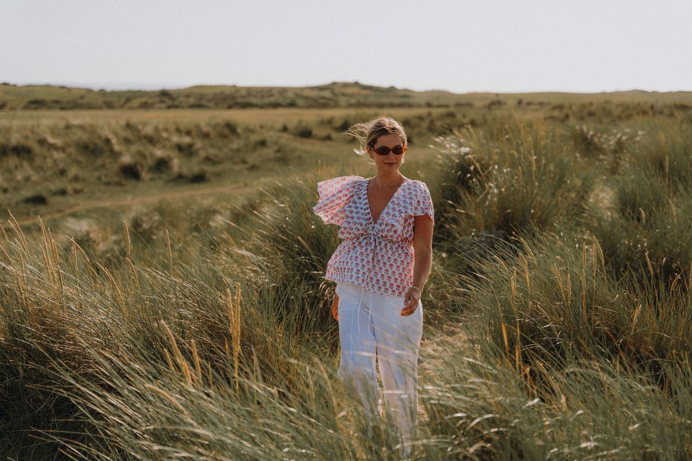 A breezy summer outfit captured among windswept coastal grasses.