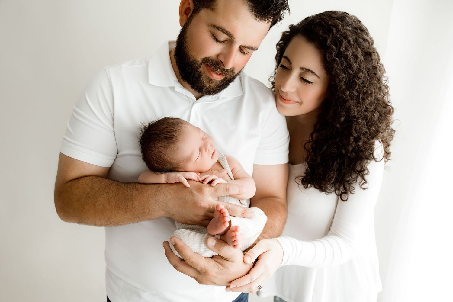 Newborn baby boy posed in dad's hands with dad and mom looking at the baby